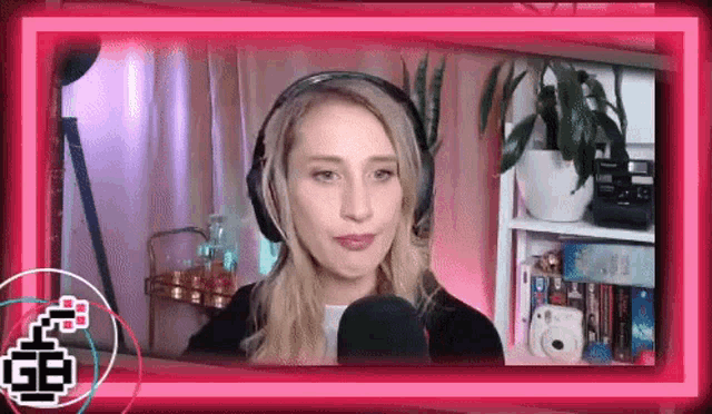 a woman wearing headphones is talking into a microphone in front of a pink background .