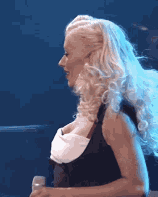 a woman with long blonde hair is holding a microphone in her hand