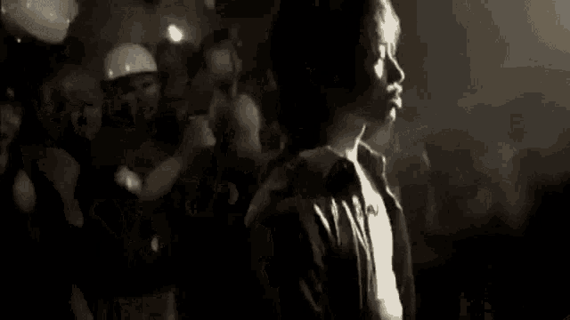 a black and white photo of a man smoking a cigarette in a dark room .