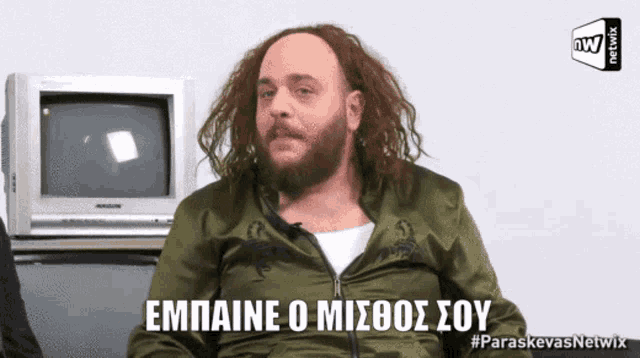 a man with a beard is sitting in front of a television with the words empaine o misboos soy written on it