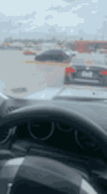 a person is driving a car in a parking lot with a lot of cars .