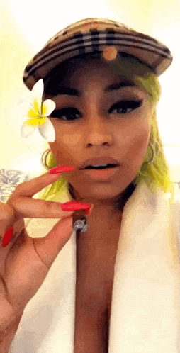 a woman with green hair is wearing a hat and holding a flower to her face .