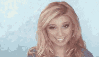 a woman with long blonde hair is smiling and looking at the camera against a blue background .