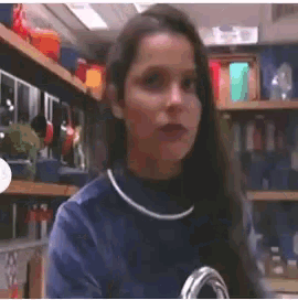 a woman in a blue sweater is standing in a room