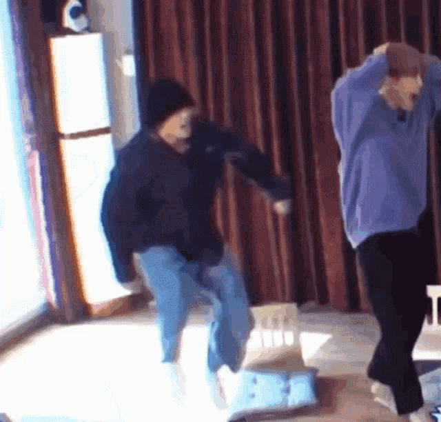 a couple of people are dancing in a room with a chair in the background .