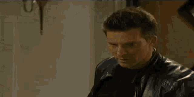 a man in a black leather jacket is standing in front of a door .