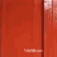 a man in a blue shirt is standing in a red doorway .