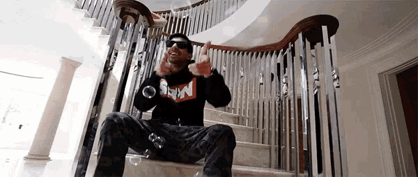 a man is sitting on a set of stairs wearing sunglasses and a sweater that says supreme
