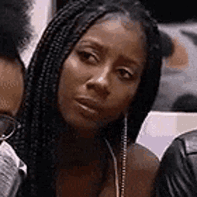a woman with braids is looking at the camera while sitting next to a man .