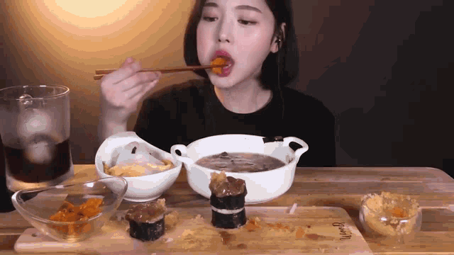 a woman is eating food with chopsticks at a table