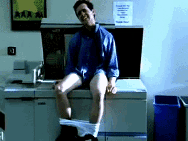 a man sitting on a counter with his pants down and a sign that says ' a ' on it
