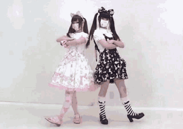 two girls are standing next to each other wearing masks and dresses .
