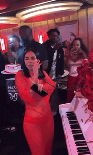 a woman in a red dress stands in front of a white piano