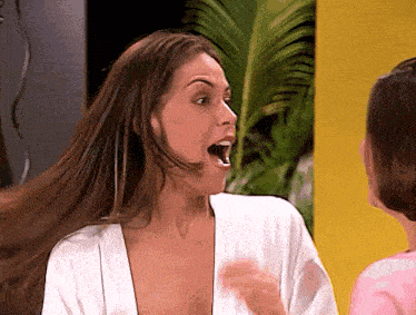 a woman in a white robe has her mouth open and her hair blowing in the wind