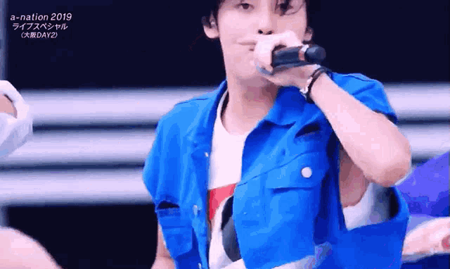 a man in a blue jacket is singing into a microphone at a nation 2019