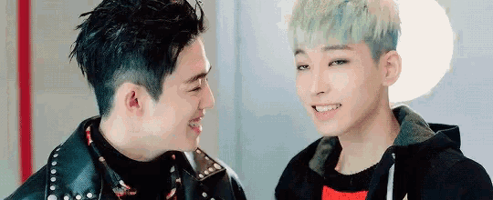 two young men are looking at each other in a room and smiling .