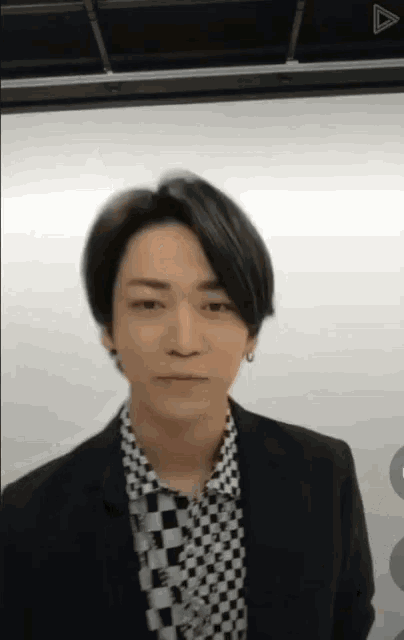 a man in a suit and a checkered shirt is looking at the camera .