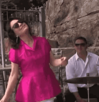 a woman in a pink shirt is dancing in front of a man in a white shirt