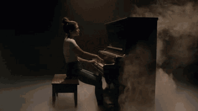 a woman sits on a bench playing a piano with smoke coming out of it