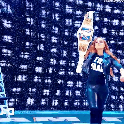 a woman is holding a championship belt in front of a blue background .