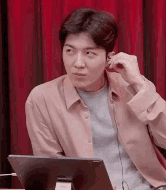 a man is wearing headphones while sitting in front of a laptop .