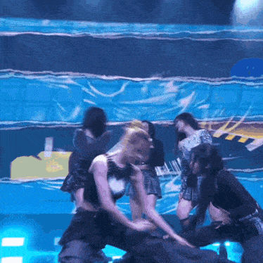a group of women are dancing on a stage in front of a blue background