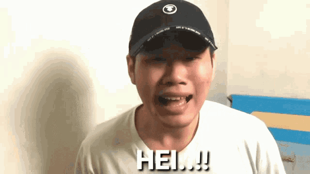 a man wearing a hat and a white shirt is saying hello