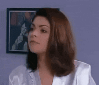 a woman in a white robe is sitting in front of a purple wall .