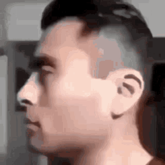 a close up of a man 's face with a shaved head and ears .
