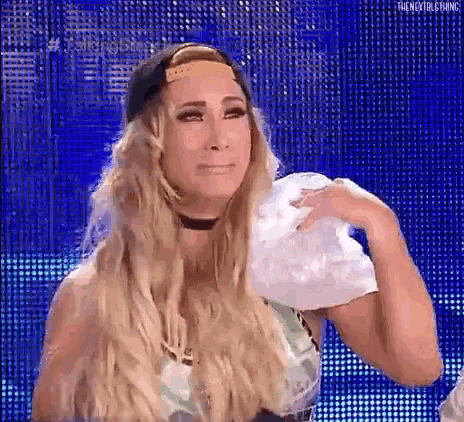 a woman with long blonde hair is holding a white towel over her shoulder .