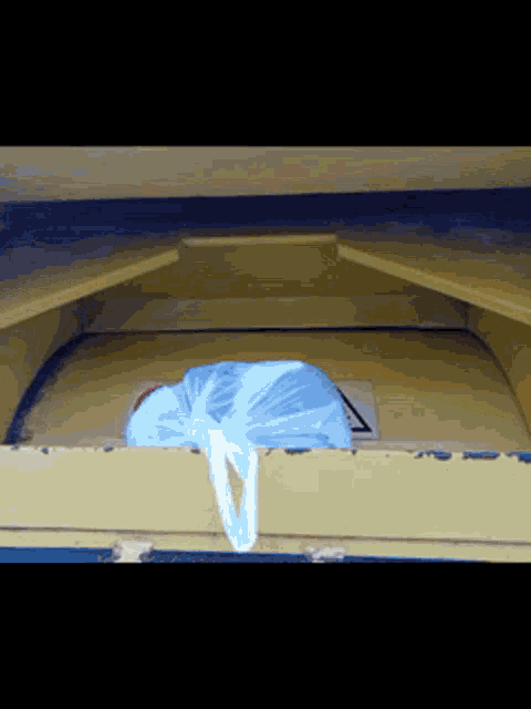 a blue plastic bag is sitting on a yellow box