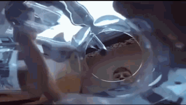 a person is looking through a glass tube with a reflection of a person in it .