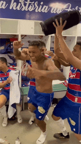 a group of soccer players are dancing in a locker room with a sign that says historia