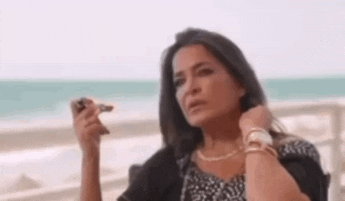 a woman is smoking a cigarette while sitting on a beach .