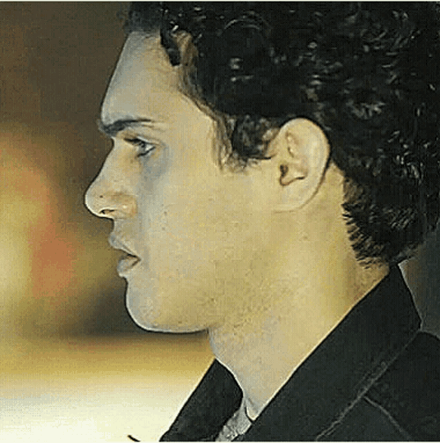 a close up of a man 's face with a black jacket on .