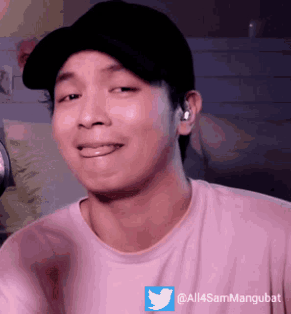 a man wearing a pink shirt and a black hat has a twitter logo on his t-shirt