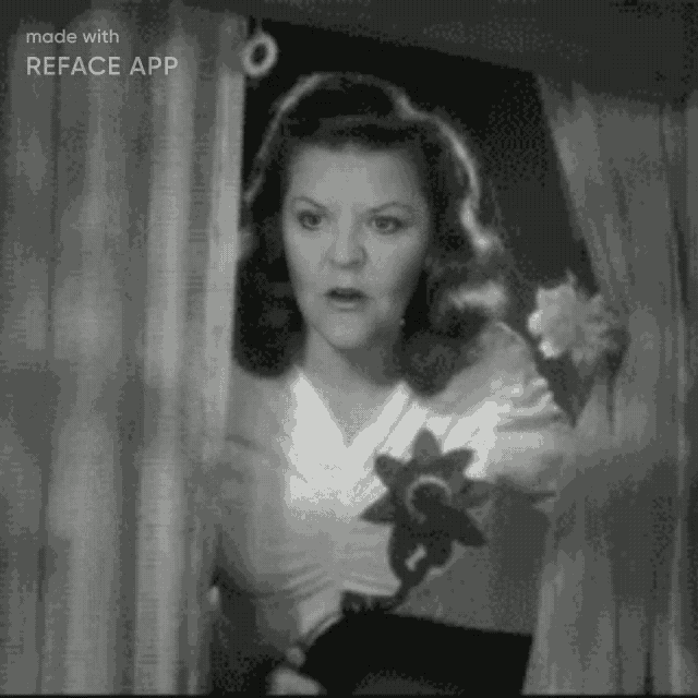 a black and white photo of a woman standing in front of a window .