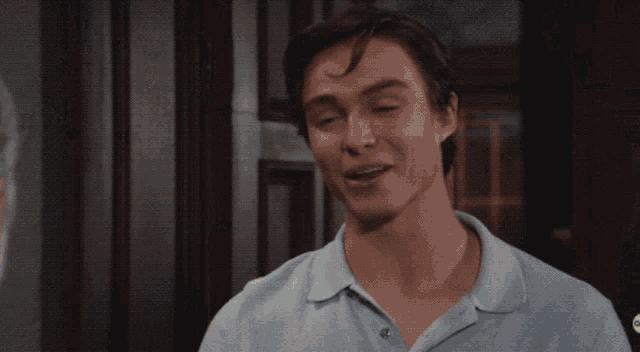 a man wearing a light blue shirt is smiling in front of a door