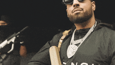 a man with a beard wears sunglasses and a black hat
