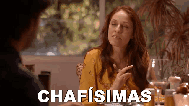 a woman is sitting at a table with a man and the word chafisima is above her