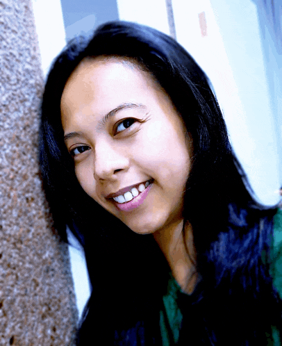a woman with long black hair and a green shirt smiles for the camera