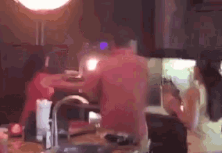 a man without a shirt is standing in a kitchen next to a woman .