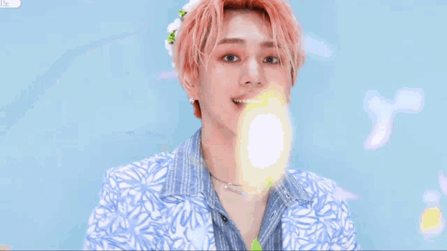 a young man with pink hair and a flower in his hair making a peace sign