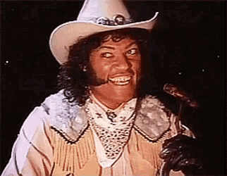 a man in a cowboy hat is smiling and holding a sausage .