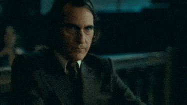 a man in a suit and tie is looking at the camera .