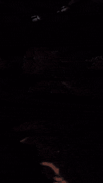 a woman is taking a selfie with her phone in a dark room .