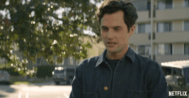 a man in a denim shirt is standing in front of a building with netflix written on the bottom