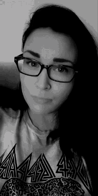 a black and white photo of a woman wearing glasses and a t-shirt that says aaa