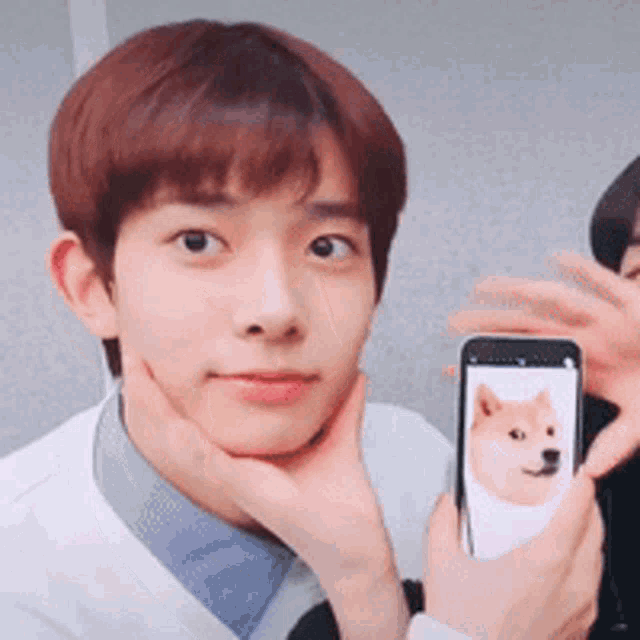 a young man is holding a cell phone with a picture of a dog on it