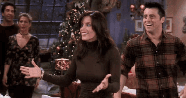a group of people standing in front of a christmas tree and smiling